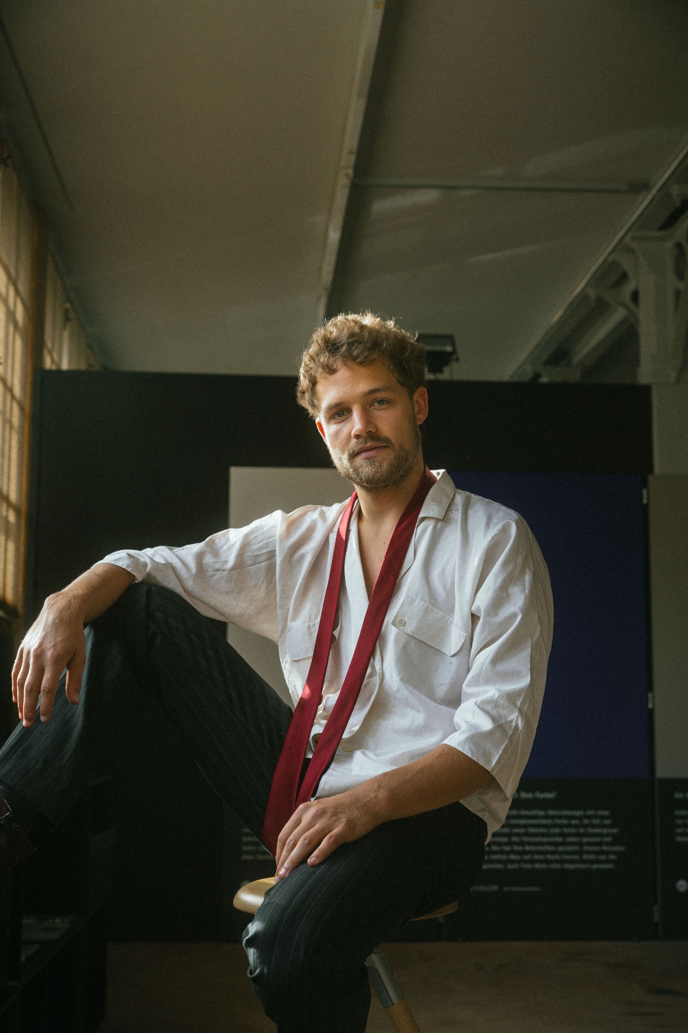 Der junge Schauspieler blickt locker da sitzend in die Kamera.