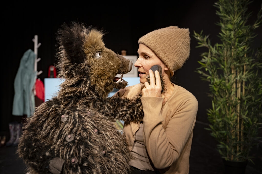 Eine Wildschweinfigur und eine Frau schauen sich in die Augen.