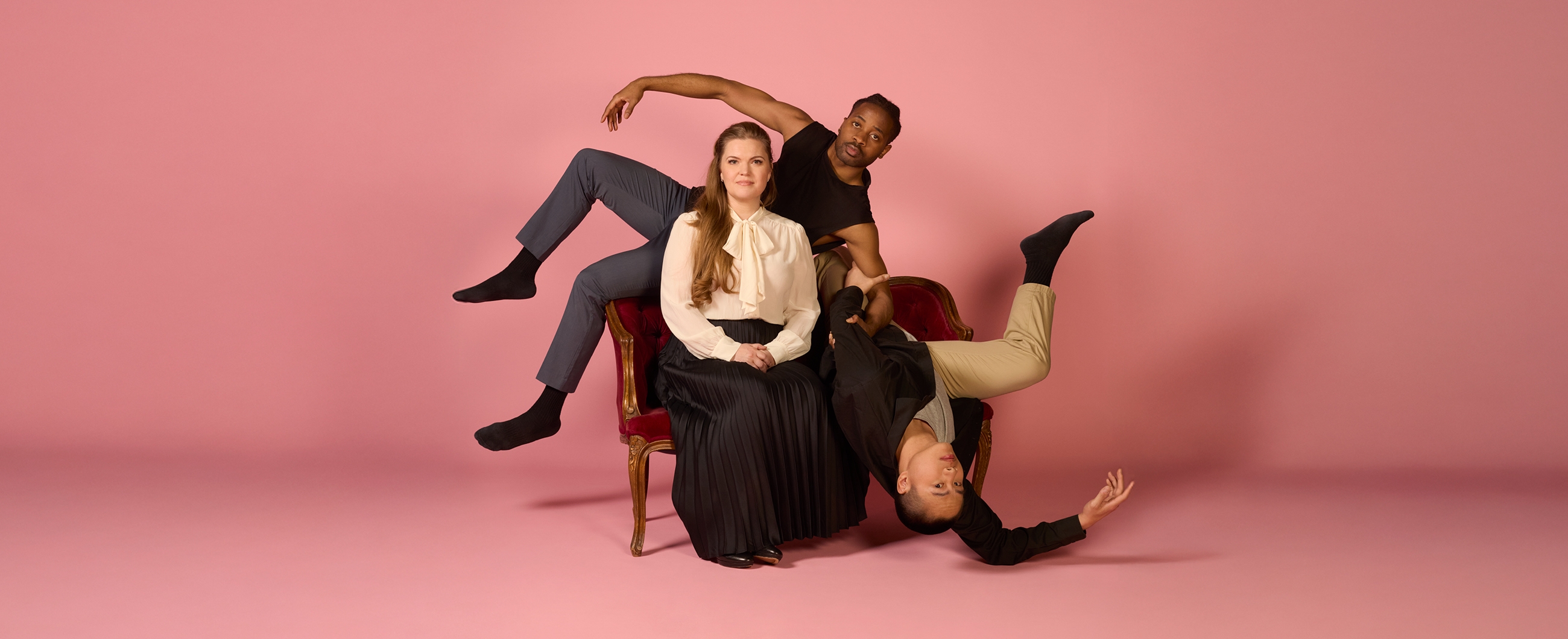 zwei tänzer umrahmen eine sitzende frau