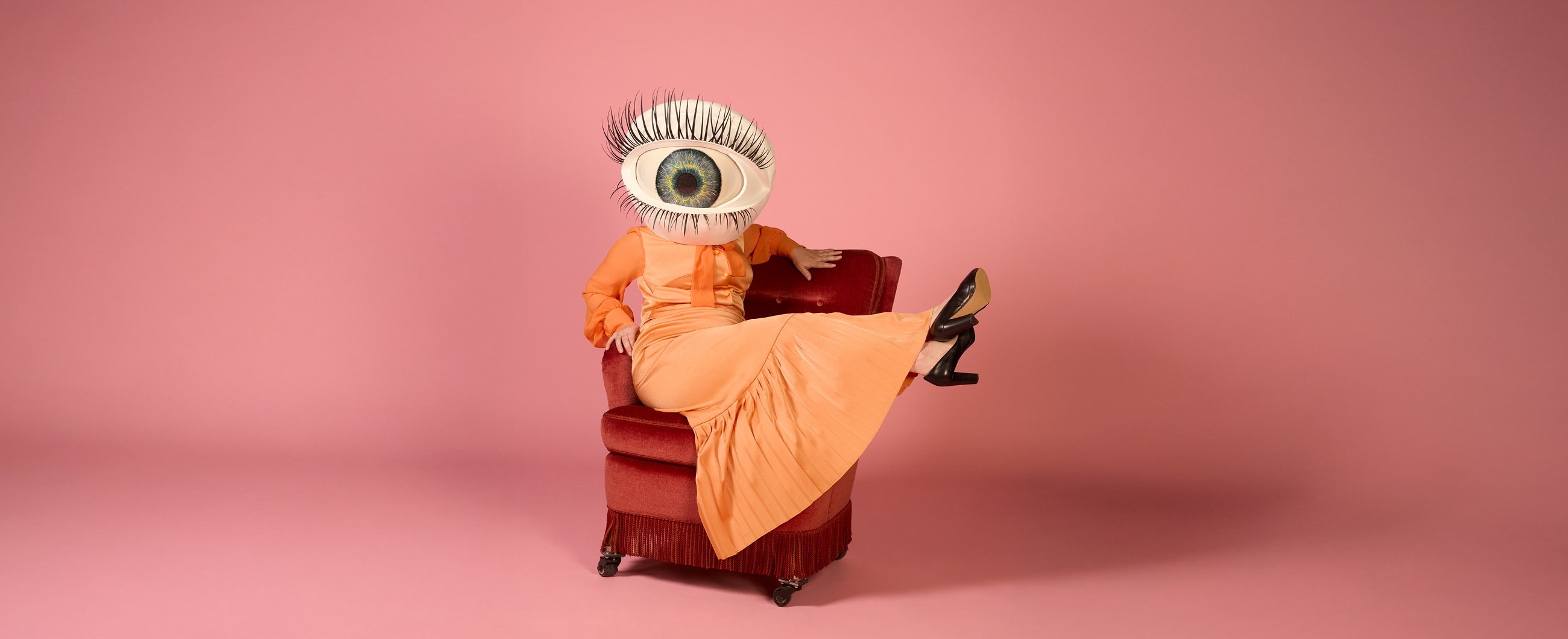 eine figur im langen kleid hat einen kopf aus grossem auge