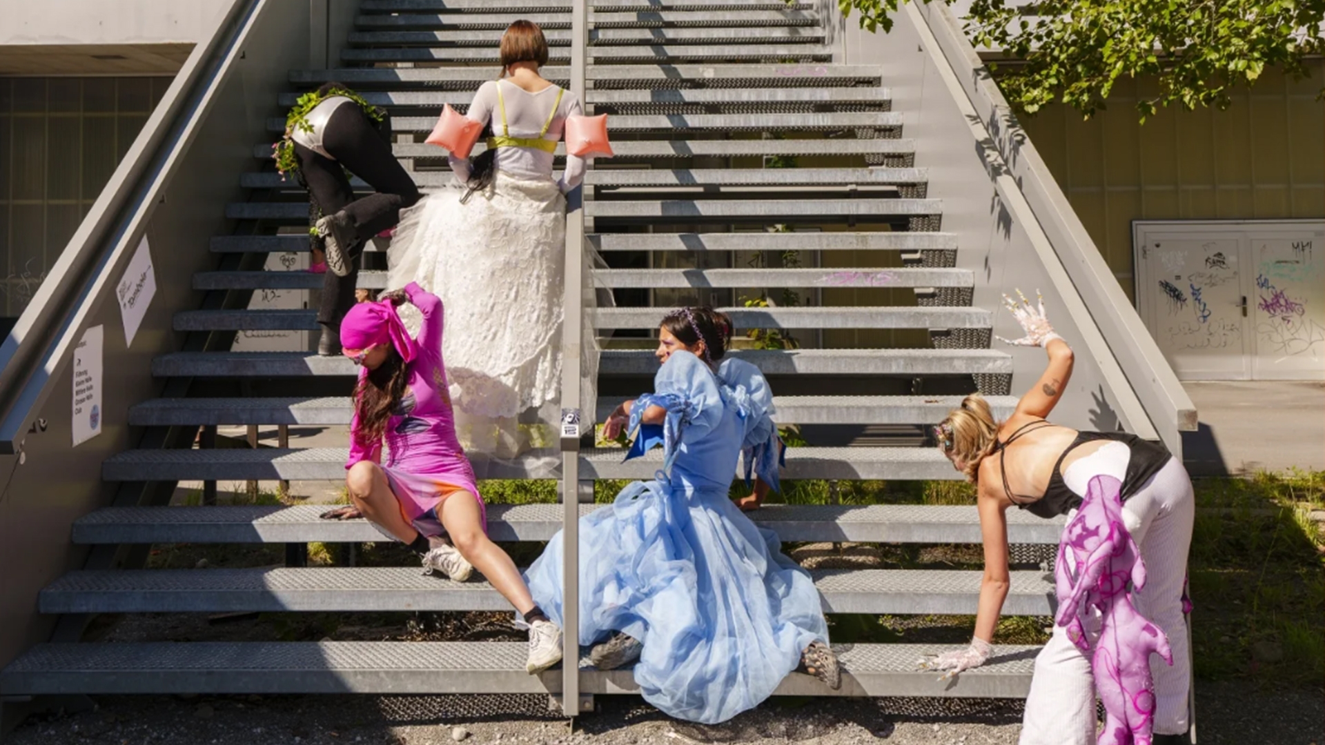 Personen in bunten Gewändern steigen eine Treppe hoch.