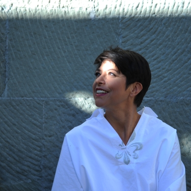 Die Sängerin blickt lächelnd nach oben, Licht fällt auf ihr Gesicht.