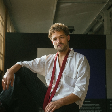 Der junge Schauspieler blickt locker da sitzend in die Kamera.